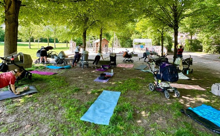 Outdoor Mama Fitness Frankfurt Mama Fitness Kurs im Sinaipark Frankfurt am Main unter Bäumen mit Sportmatten und Kinderwagen.